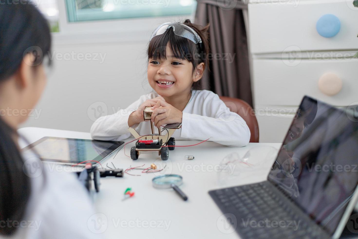 os alunos da ásia aprendem em casa na codificação de carros robóticos e cabos de placa eletrônica em haste, vapor, código de computador de tecnologia de ciência de engenharia matemática em robótica para o conceito de crianças. foto