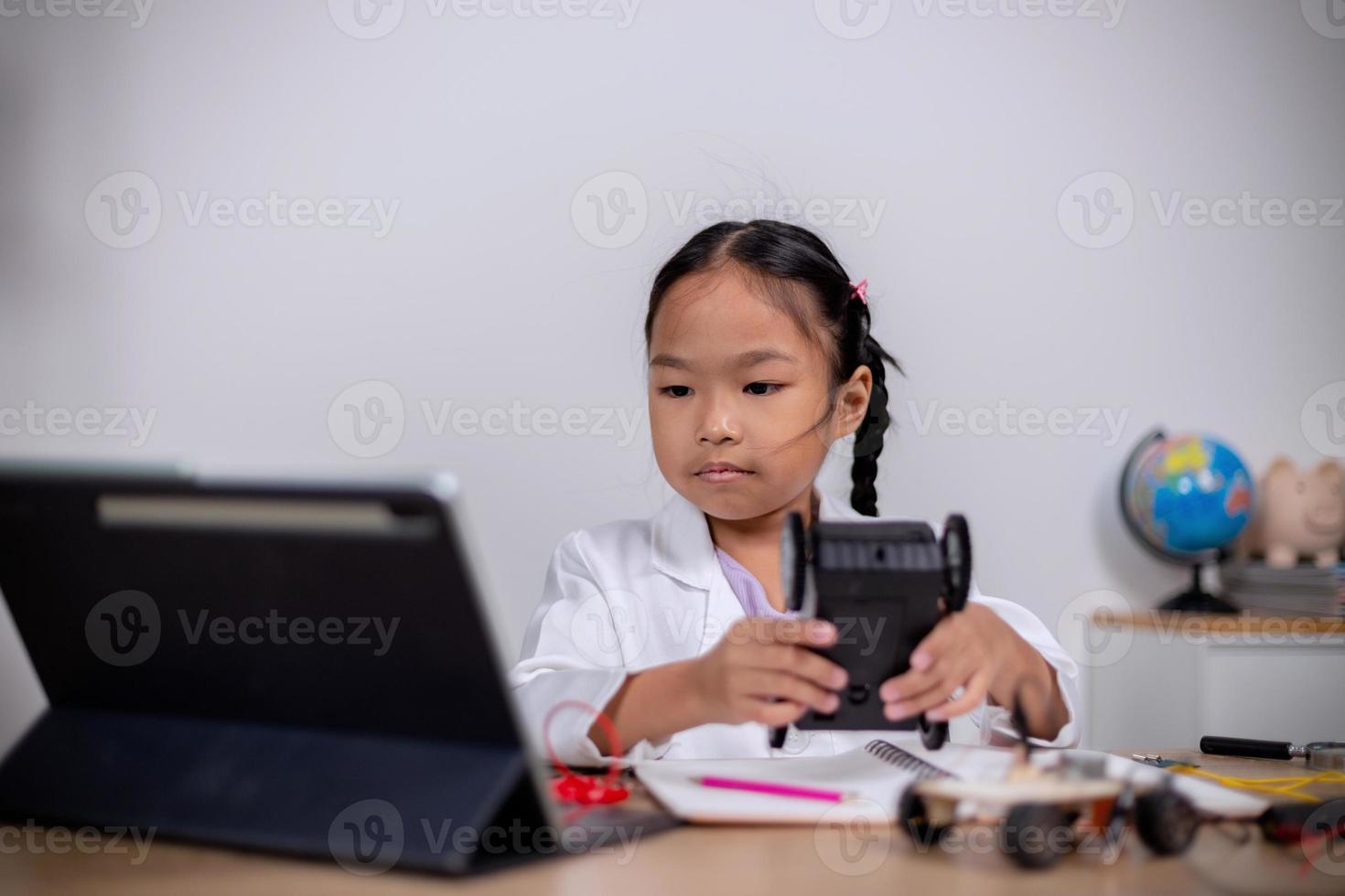 estudantes asiáticos aprendem em casa codificando carros robôs e cabos de placas eletrônicas em haste, vapor, matemática engenharia ciência tecnologia código de computador em robótica para conceitos infantis. foto