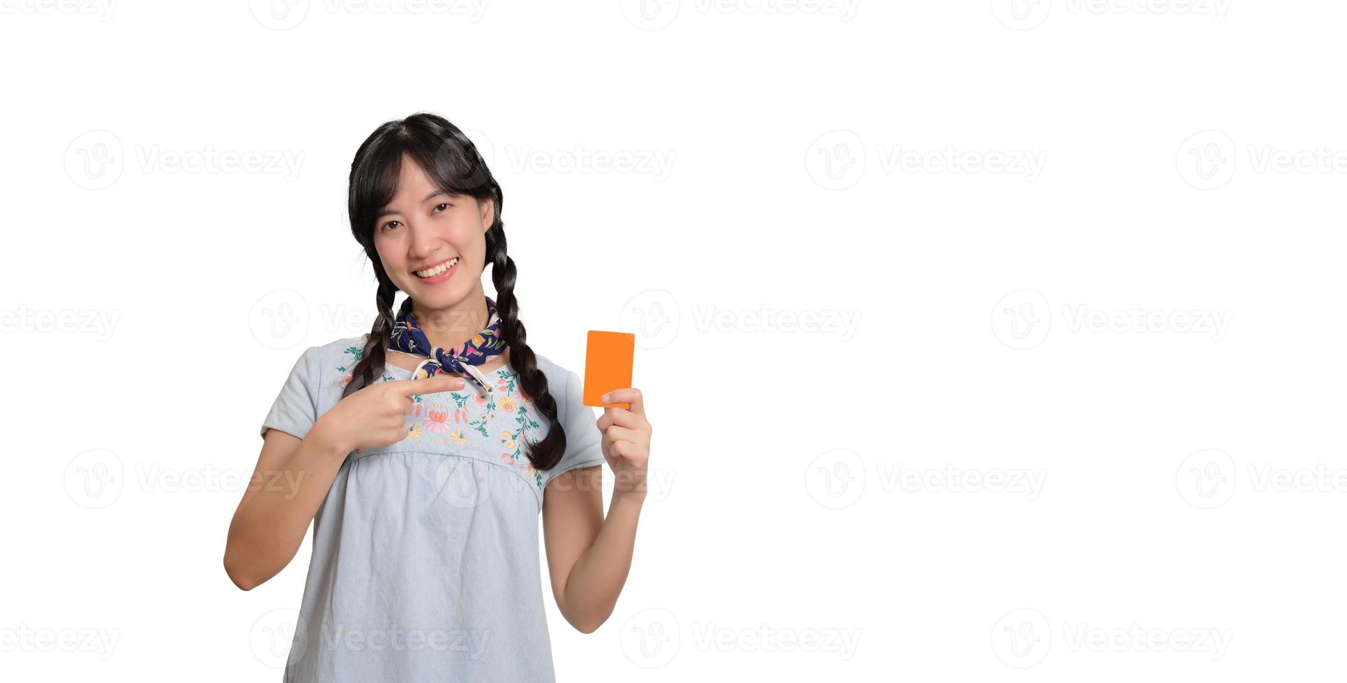 retrato de uma bela jovem asiática feliz em vestido jeans segurando cartão de crédito em fundo branco foto