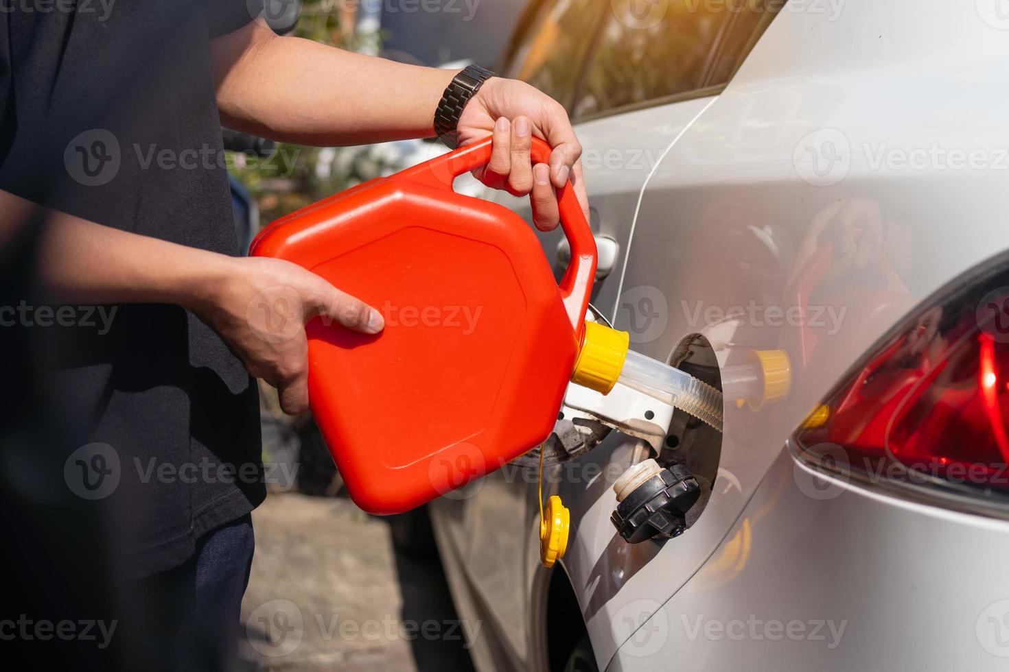 homem enche o combustível no tanque de gasolina do carro a partir de uma vasilha vermelha ou lata de combustível de plástico conceito de carro de reparo de manutenção, foco seletivo foto