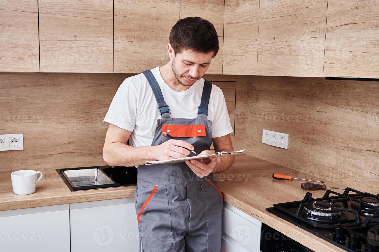 encanador assina um contrato para os serviços na cozinha foto