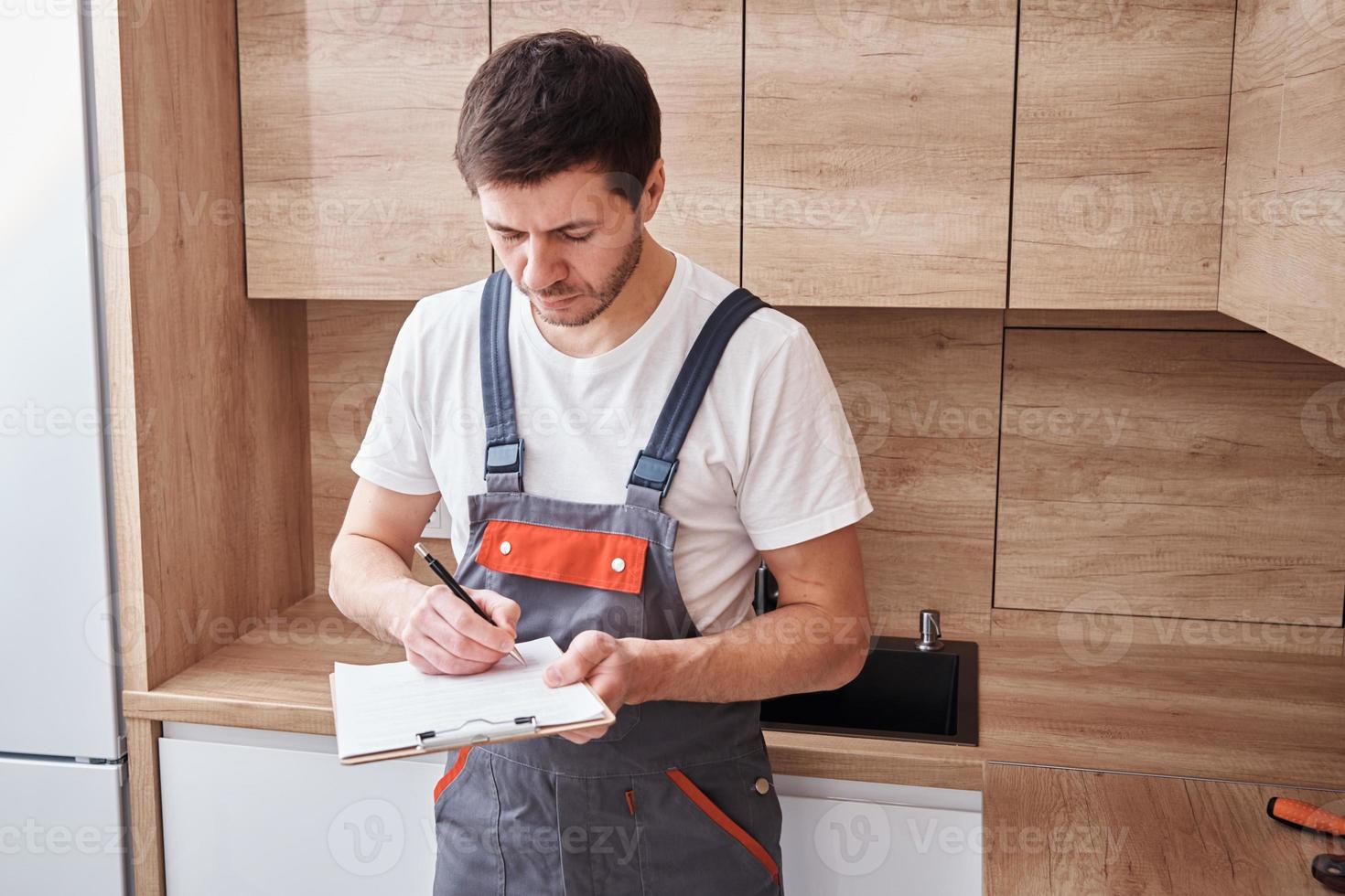 encanador assina um contrato para os serviços na cozinha foto