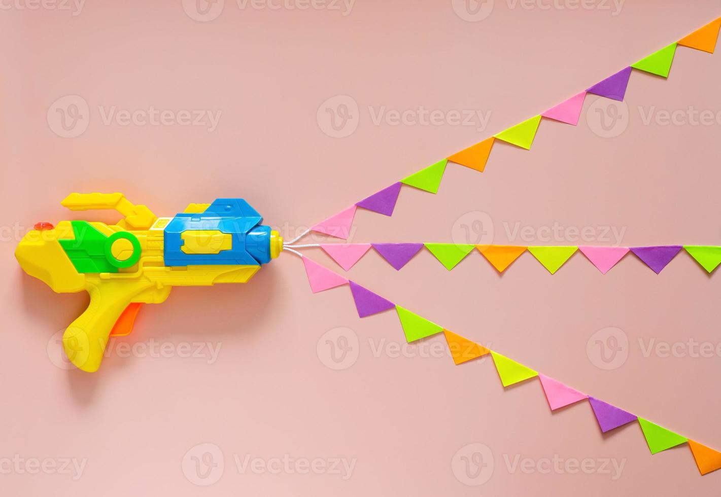 spray de pistola de água com bandeira de festa colorida para celebração do festival songkran em fundo de cor rosa. conceito mínimo de férias. foto