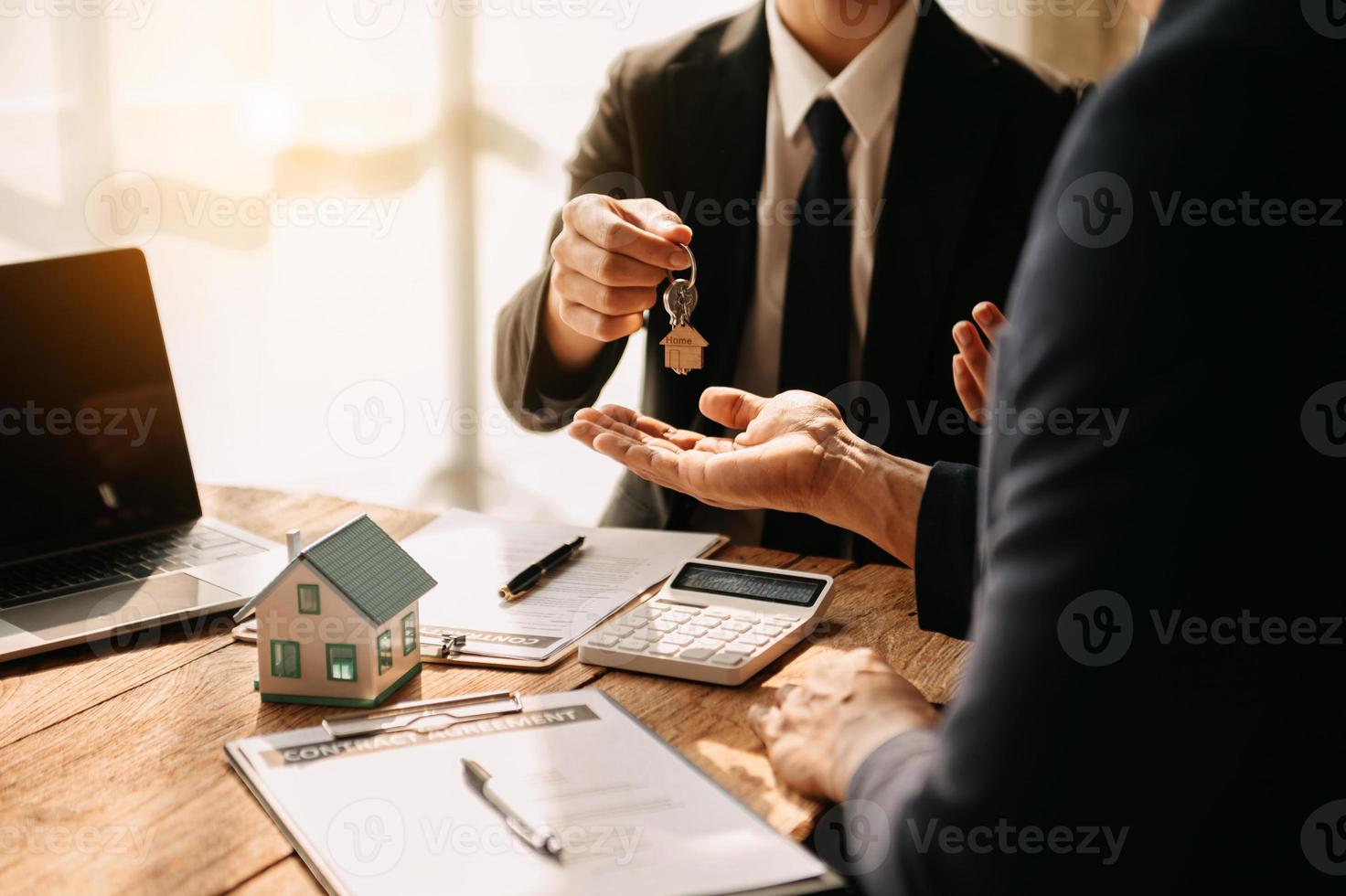 comprar uma casa ou seguro, um agente de seguros apontando uma caneta para os interessados em alugar uma casa, um contrato, assinar um contrato de compra de casa no escritório foto