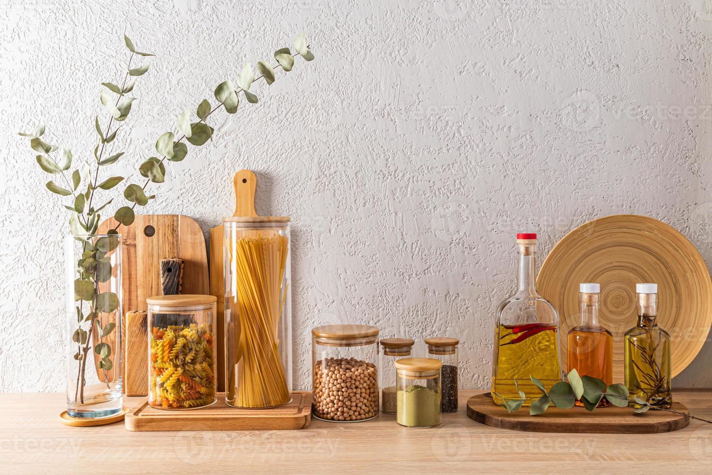 vários tipos de tábuas de corte, prato de bambu, potes de vidro e garrafas de produtos culinários. bancada estilosa. vista frontal. foto