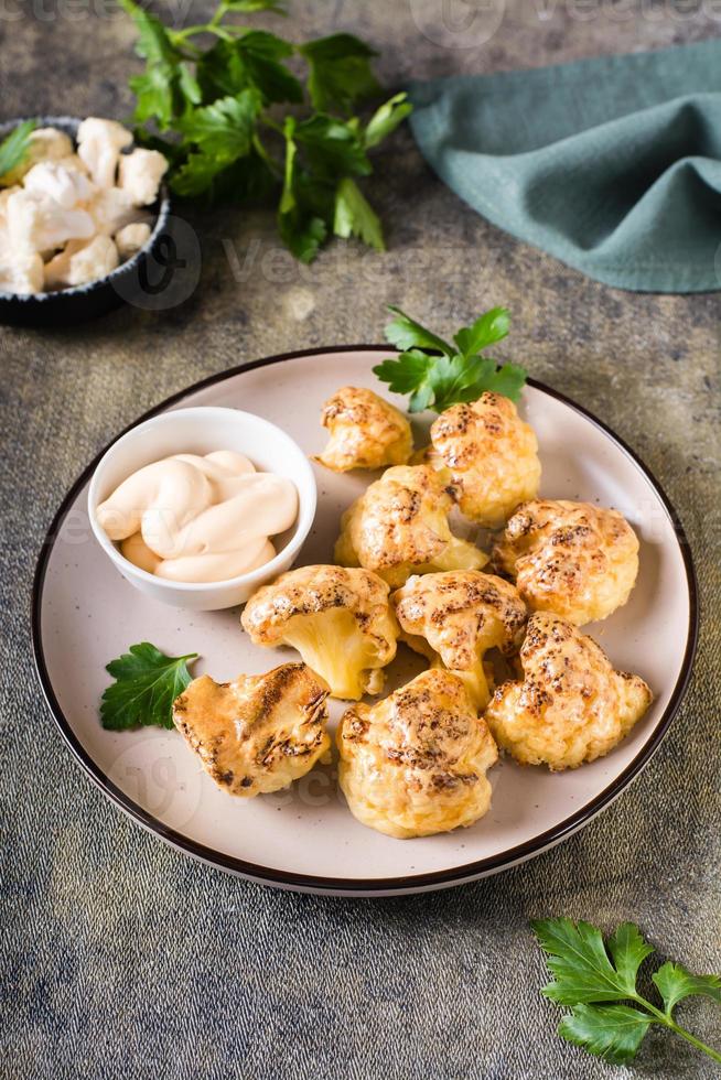 asas de búfalo de couve-flor vegetariana e molho em um prato na mesa. visão vertical foto