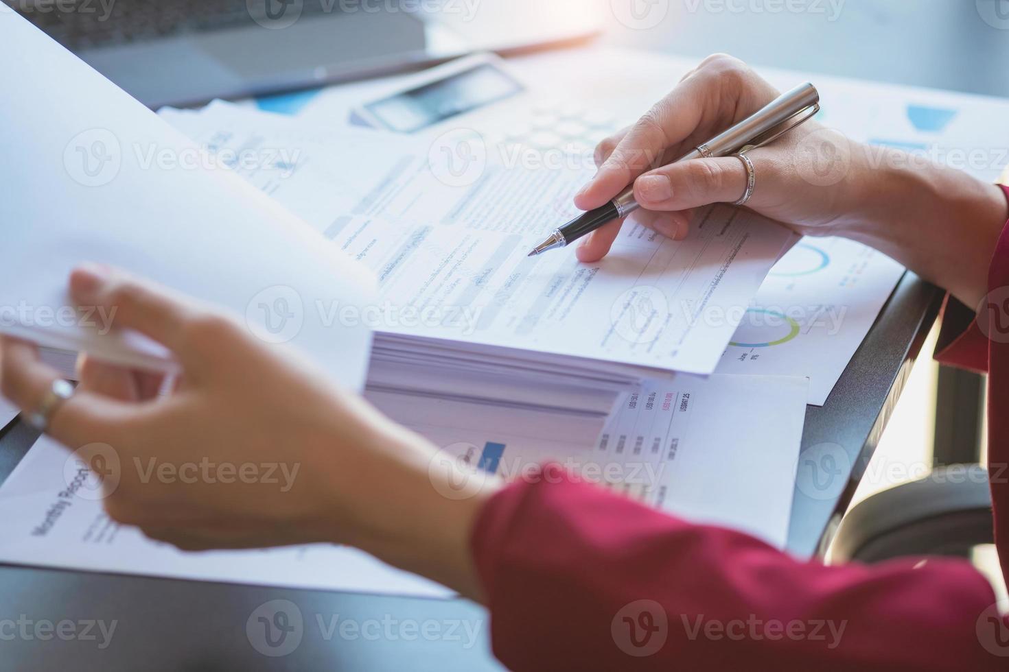 financeira, empresária asiática de terno vermelho segurando a xícara de café sentada na mesa no escritório, tendo computador para fazer trabalho de contabilidade no local de trabalho para calcular o lucro anual por dever, ideia de negócio foto