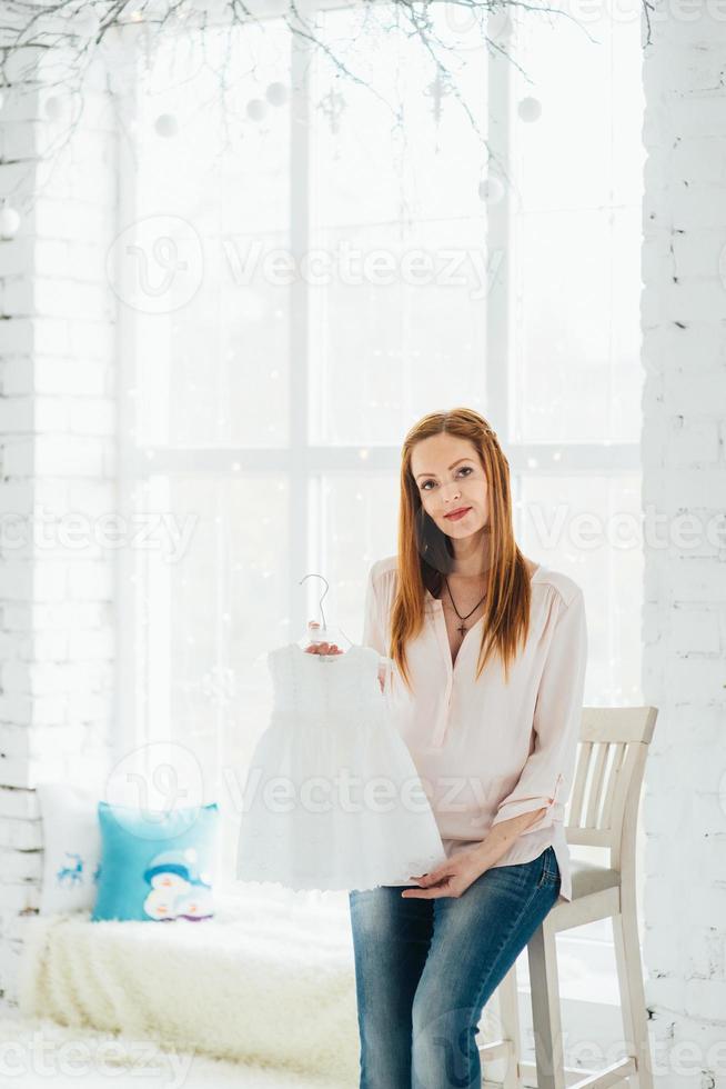 uma garota ruiva grávida em uma blusa leve e jeans azul foto