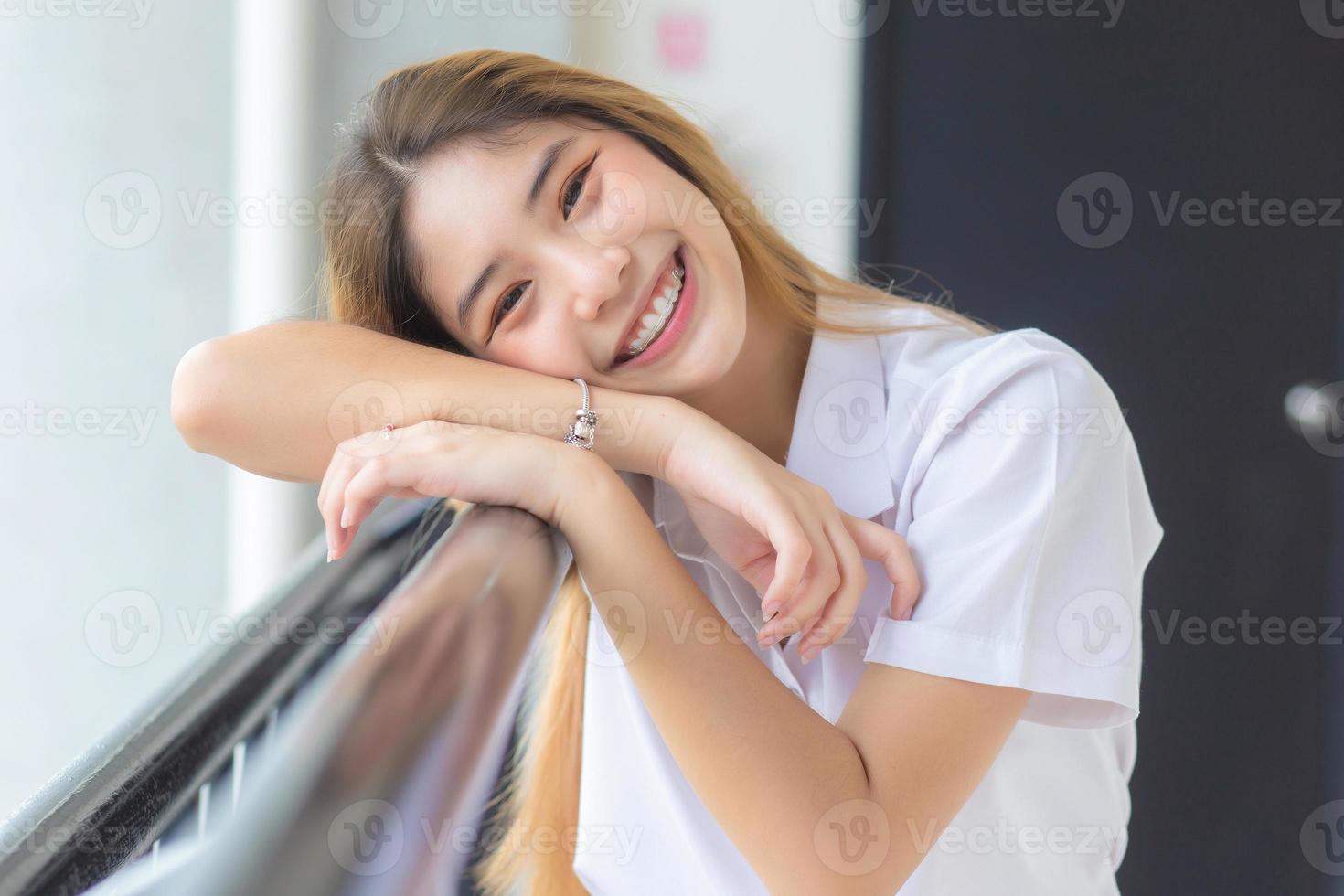 linda e bonita jovem estudante asiática em uniforme de estudante universitário tailandês sorrindo com confiança e olhando para a câmera no fundo da universidade foto