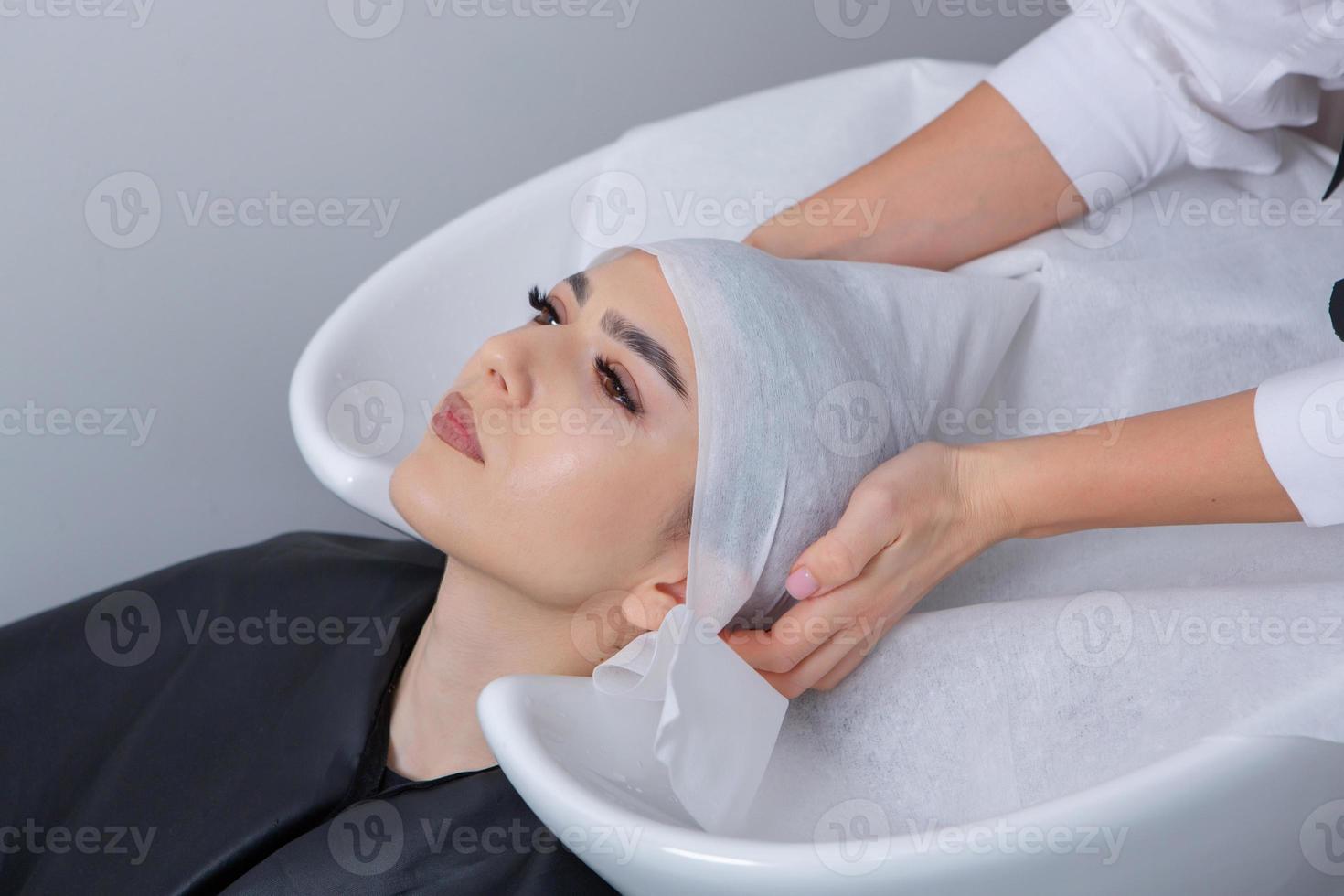 cabeleireiro profissional lavando o cabelo de jovem no salão de beleza. close-up do cabelo da mulher no salão de beleza, conceito de penteado foto