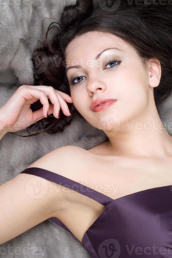jovem mulher deitada no casaco de pele cinza foto