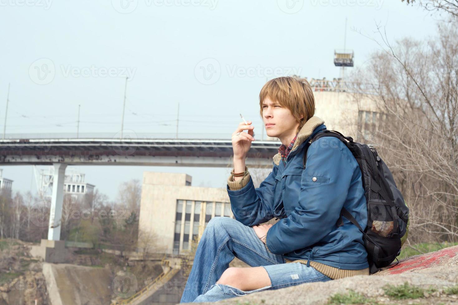 o cara sentado com um cigarro ao ar livre 2 foto