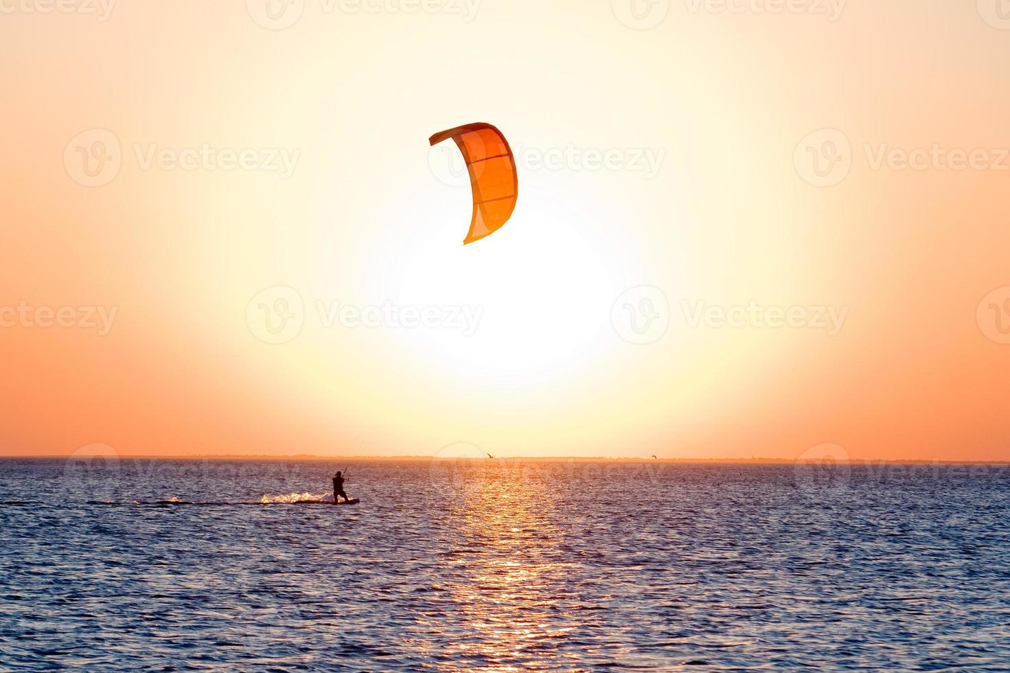 silhueta de um kitesurfista em um golfo em um pôr do sol foto