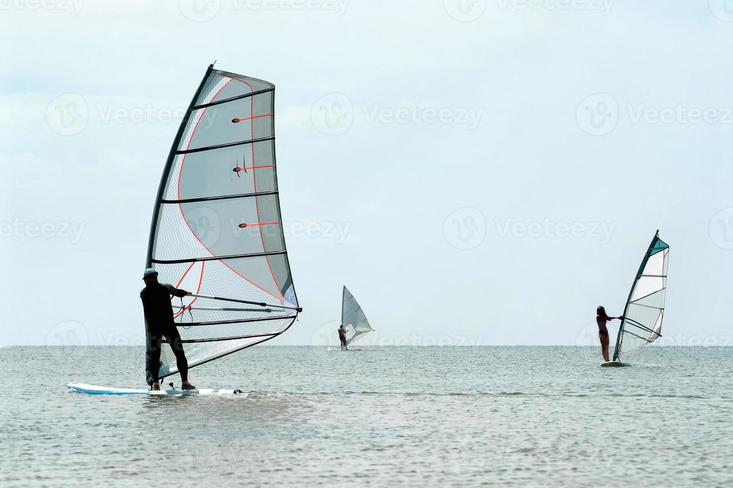 silhuetas de três windsurfistas foto