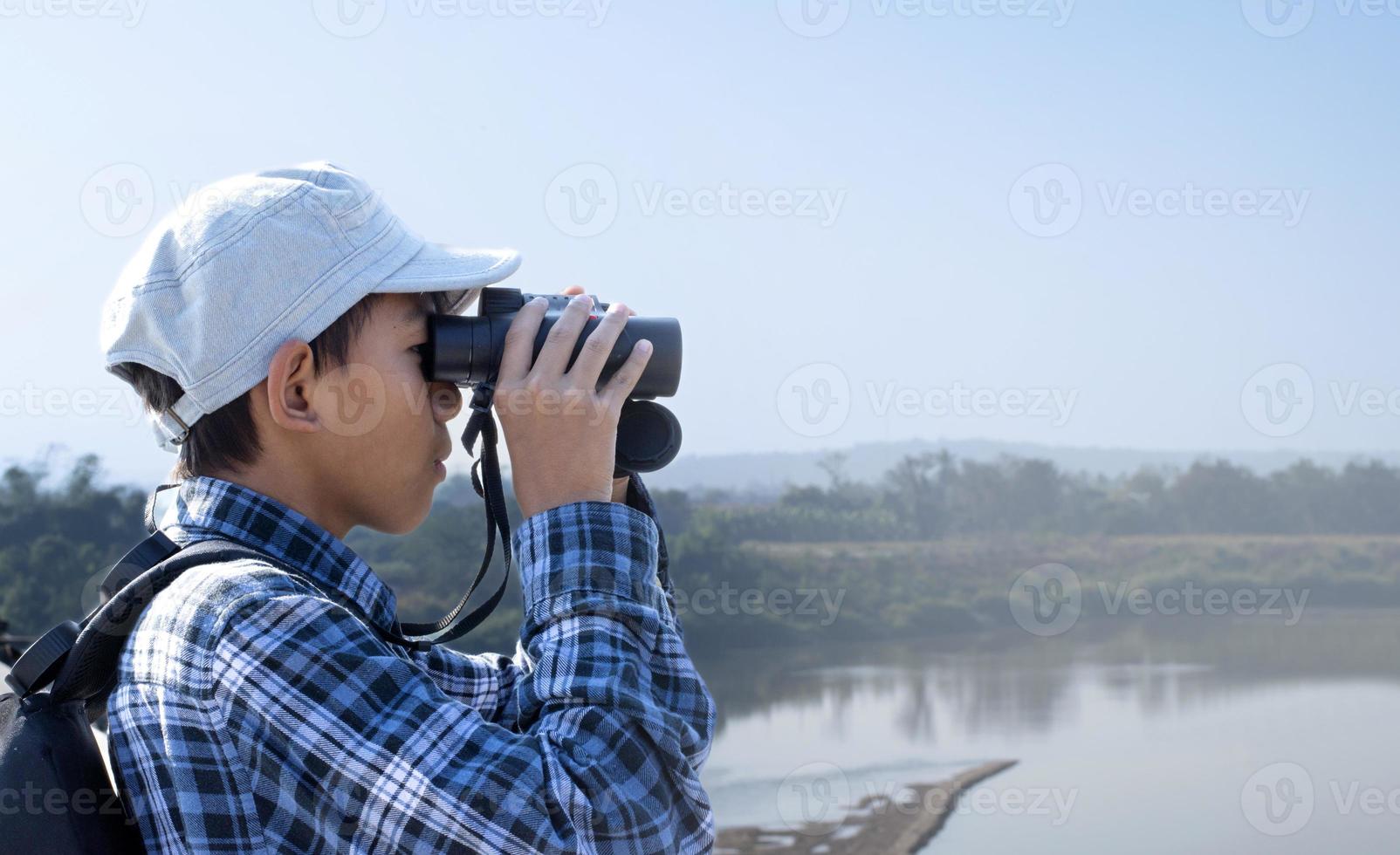 meninos asiáticos usando binóculos para observar pássaros em árvores e pescar no rio no parque nacional local durante o acampamento de verão, ideia para aprender criaturas e animais selvagens e insetos fora da sala de aula. foto