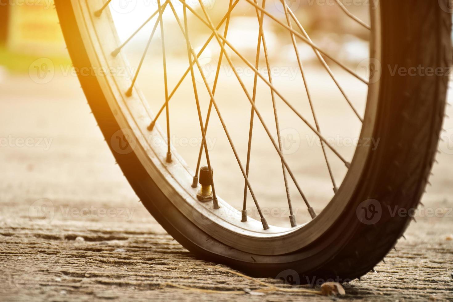 visão aproximada da roda furada da bicicleta ou do pneu furado da bicicleta que estacionou na estrada e esperando para consertar. foto