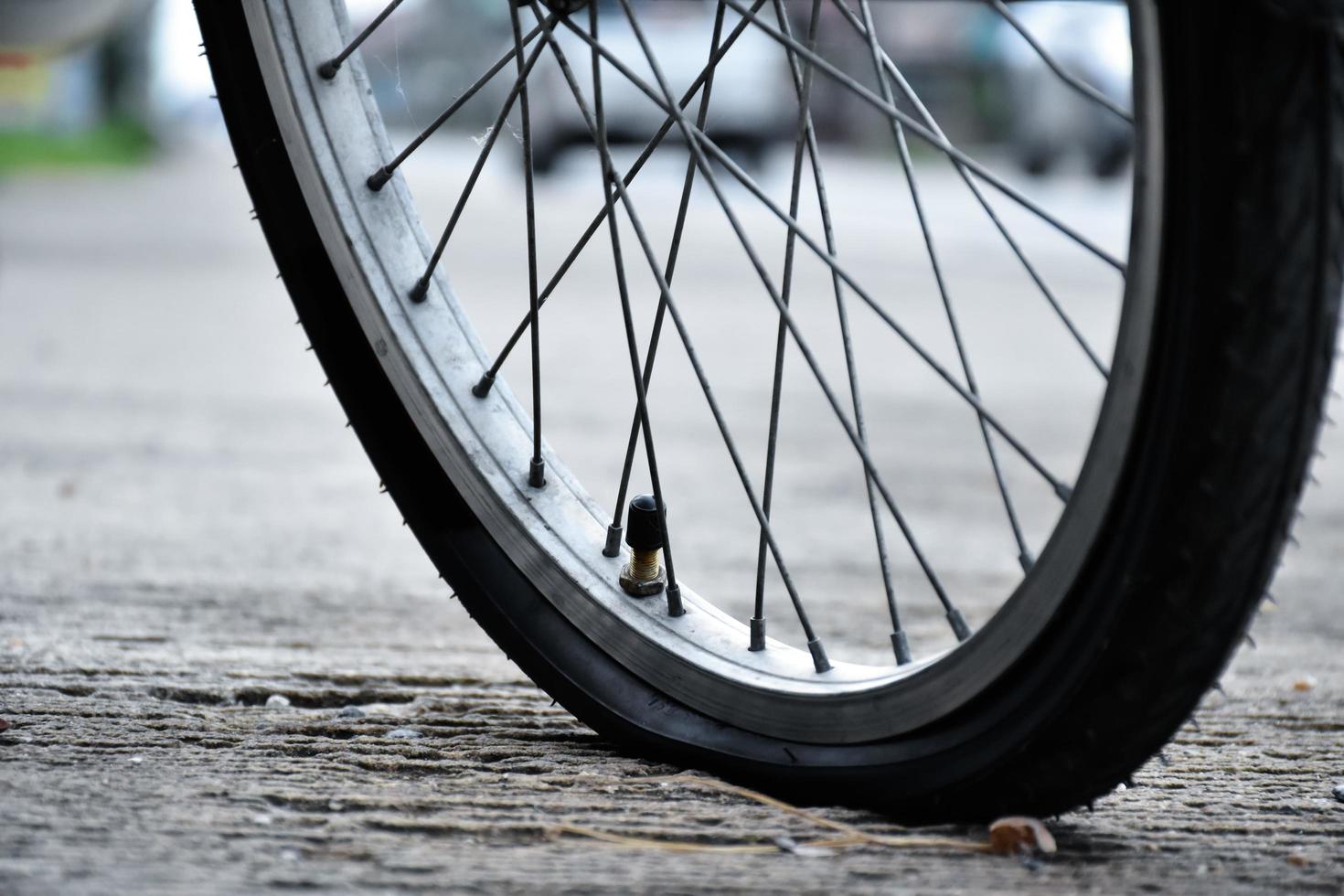 visão aproximada da roda furada da bicicleta ou do pneu furado da bicicleta que estacionou na estrada e esperando para consertar. foto