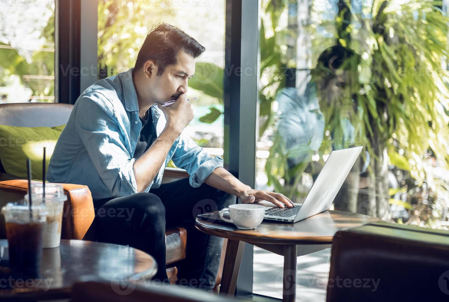 freelancer asiático de blazer com laptop no café perto da janela profissão é blogueiro, tradutor freelancer e escritor. tradutor freelance trabalha em cafeteria. aprendizagem online foto