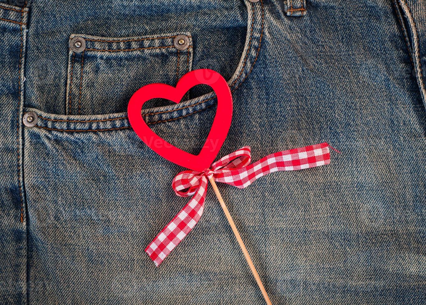 coração de madeira vermelho sobre um fundo de jeans azul desgastado foto
