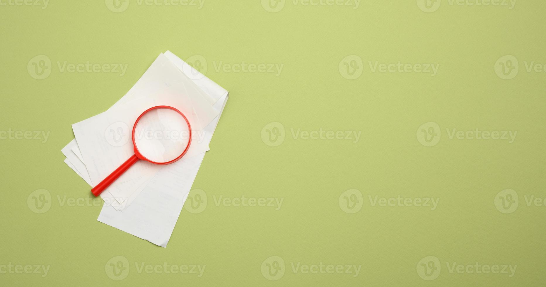 pilha de recibos de vendas de papel e lupa de plástico vermelha sobre um fundo verde. o conceito de controle de despesas e receitas foto