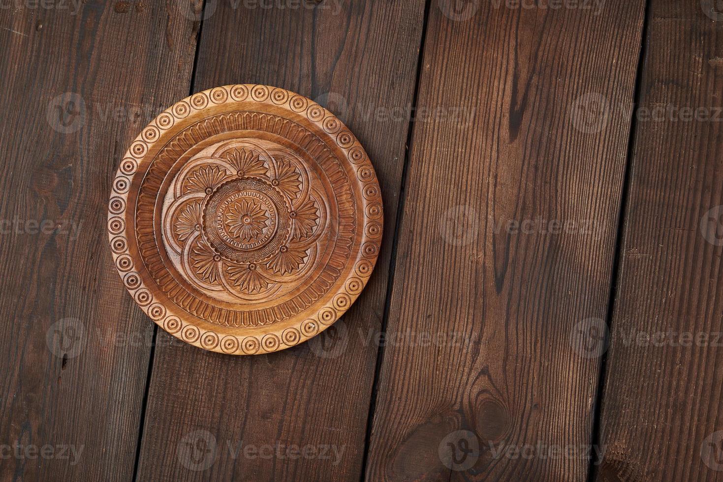 placa decorativa esculpida marrom redonda vazia em pé sobre um fundo de madeira foto