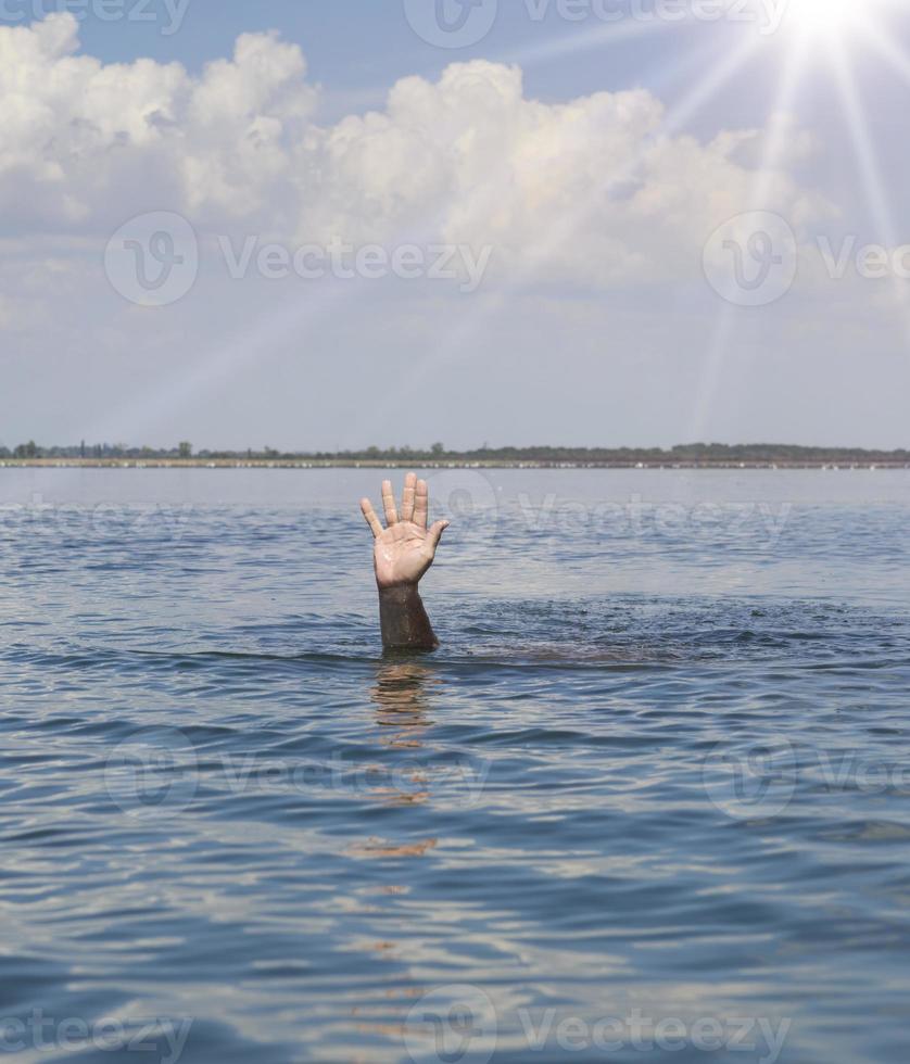 a mão do homem se projeta da água no meio do oceano foto