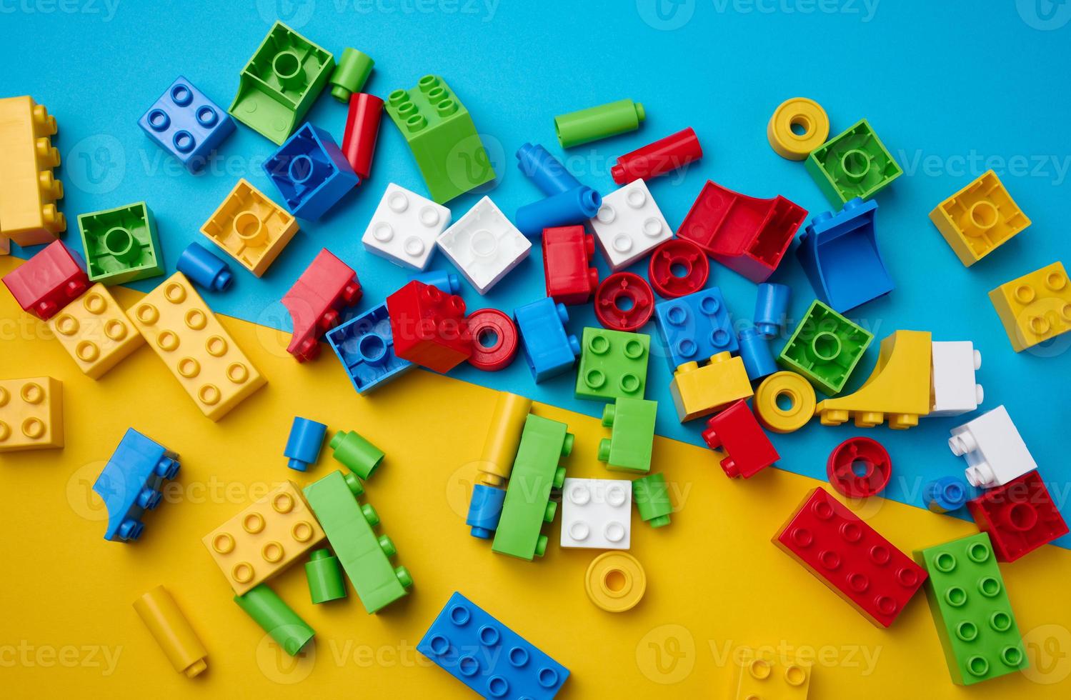 partes espalhadas de um designer infantil de plástico, vista superior. fundo azul amarelo foto