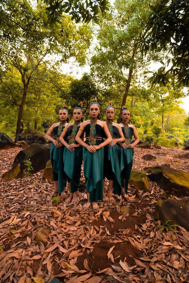 uma linda mulher asiática em uma fantasia verde juntos na frente da floresta com folhas marrons foto