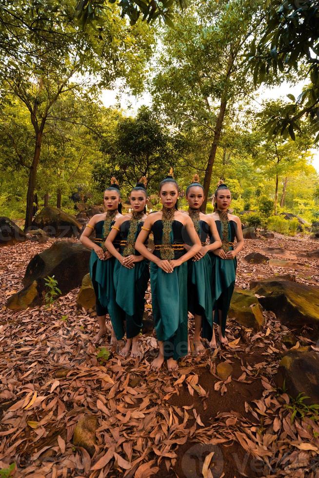 uma linda mulher asiática em uma fantasia verde juntos na frente da floresta com folhas marrons foto