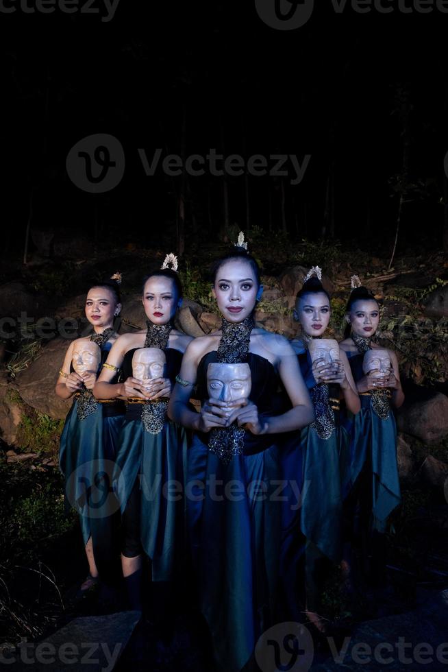 um grupo de mulheres balinesas se alinha com a máscara de madeira em suas mãos enquanto veste trajes de dança tradicional foto