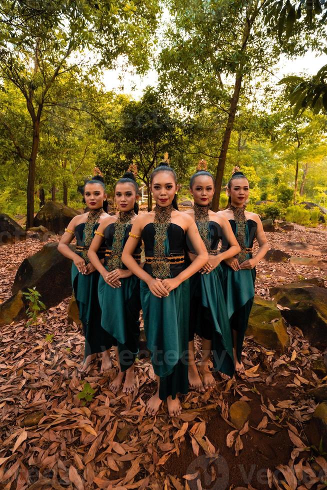 uma linda mulher asiática em uma fantasia verde juntos na frente da floresta com folhas marrons foto