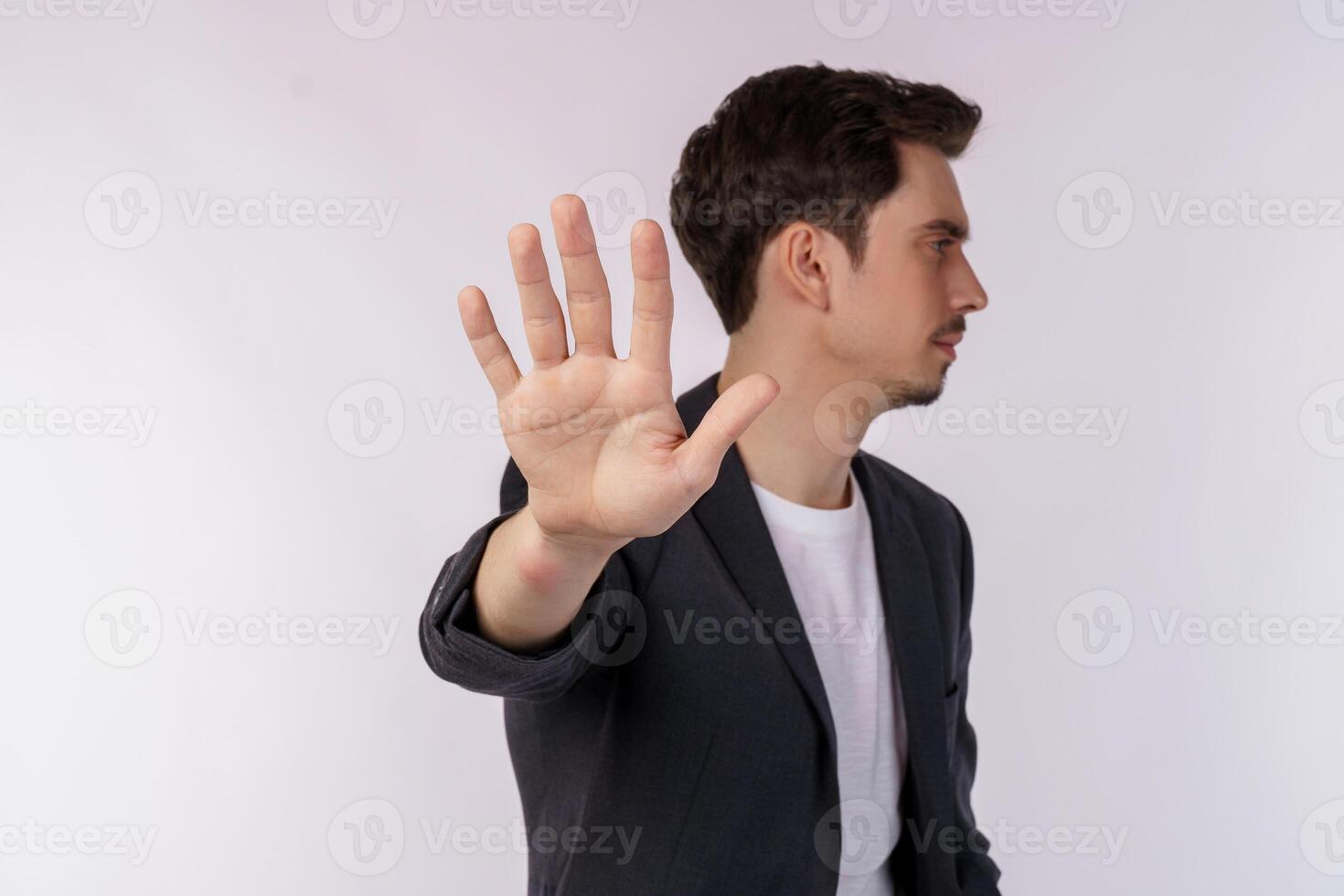 retrato do jovem empresário bonito fazendo parar de cantar com a palma da mão sobre fundo branco foto