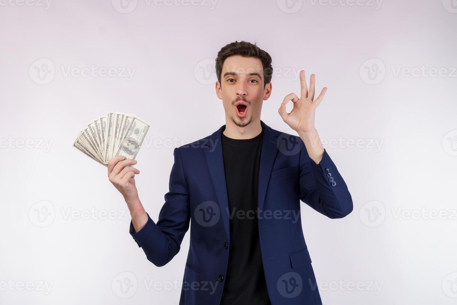 retrato de um homem alegre mostrando sinal ok e segurando dinheiro sobre fundo branco foto