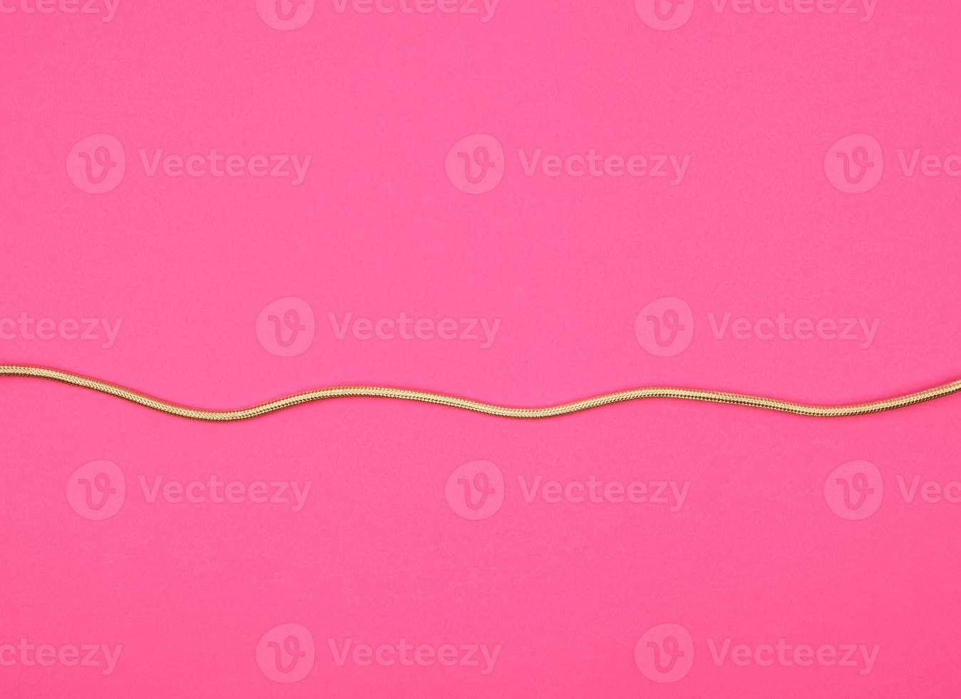 cabo dourado para equipamentos em enrolamento têxtil em um fundo rosa foto