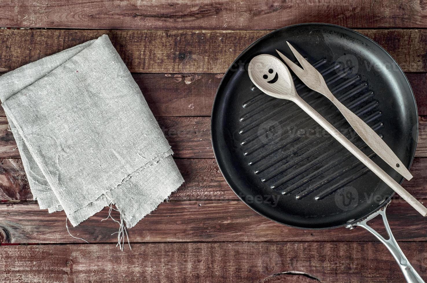 grelhar panela e utensílios de cozinha de madeira em uma superfície de madeira marrom foto