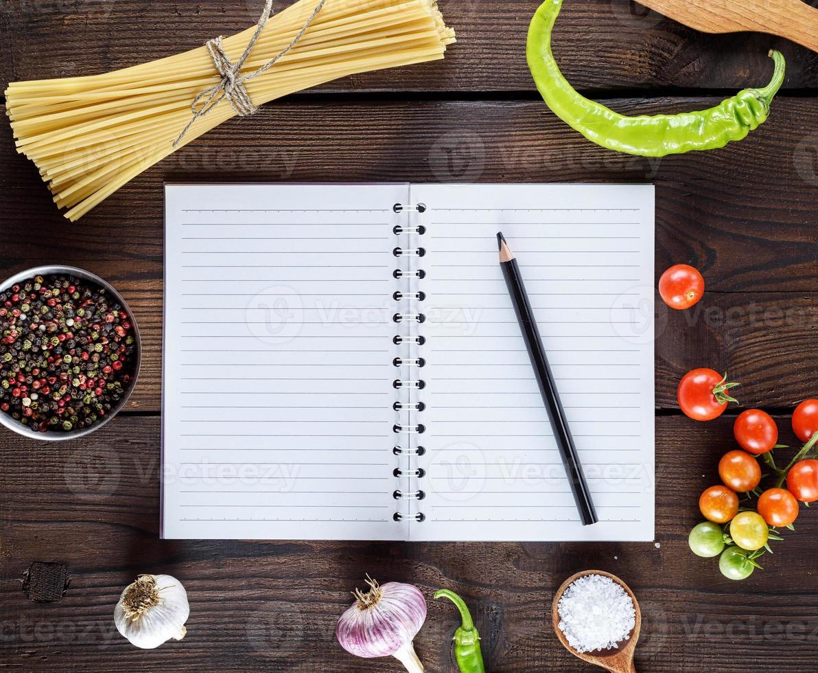 caderno em branco com folhas brancas, pasta longa crua e ingredientes para cozinhar foto