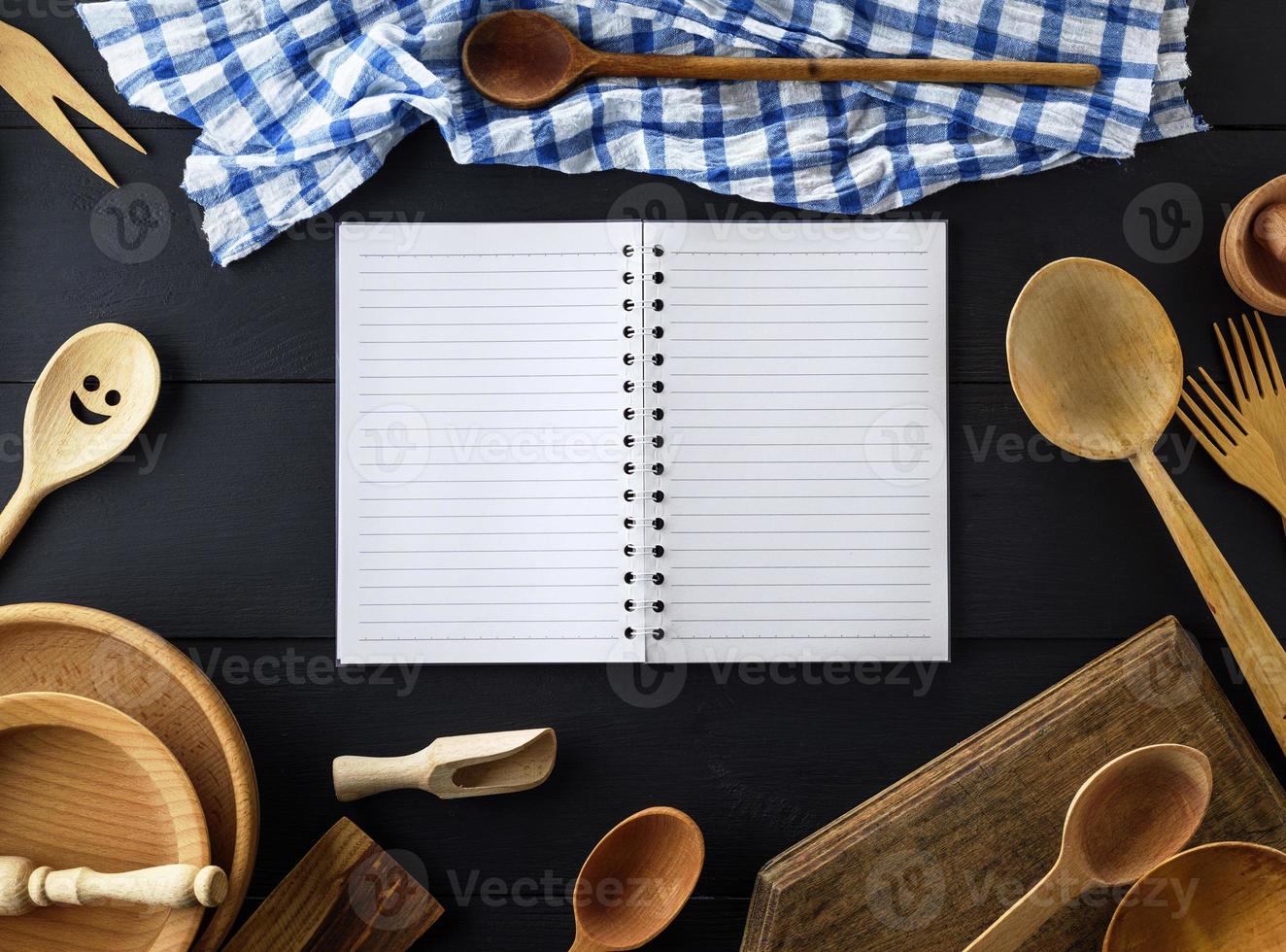 abra o caderno de papel vazio com folhas brancas em uma linha em uma mola no meio de itens de cozinha de madeira foto