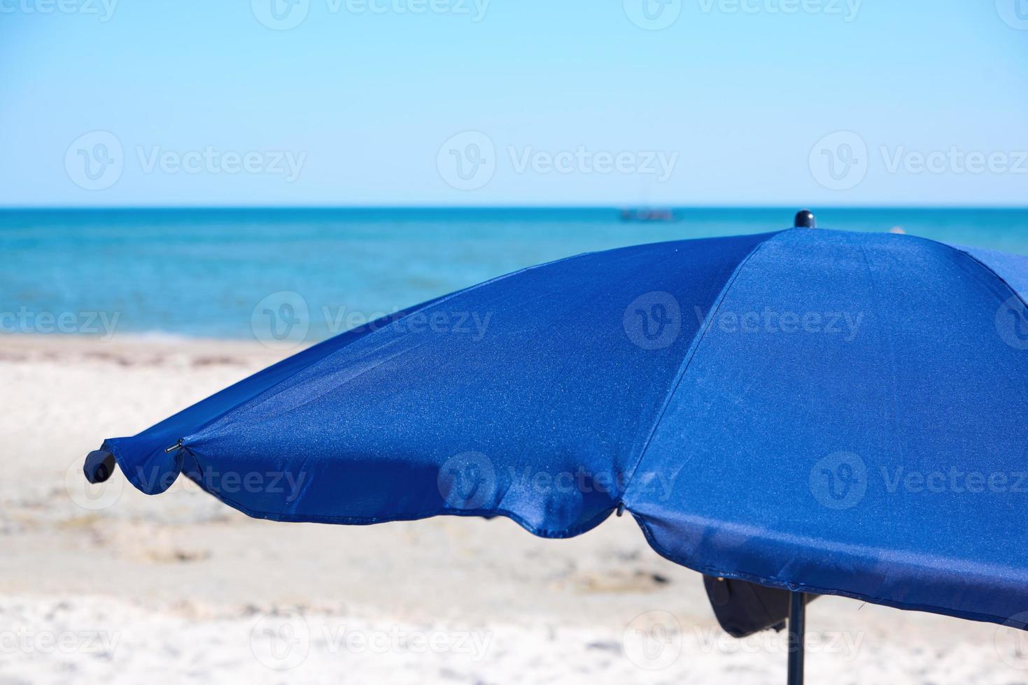 guarda-chuva de praia têxtil azul aberto em uma praia arenosa foto