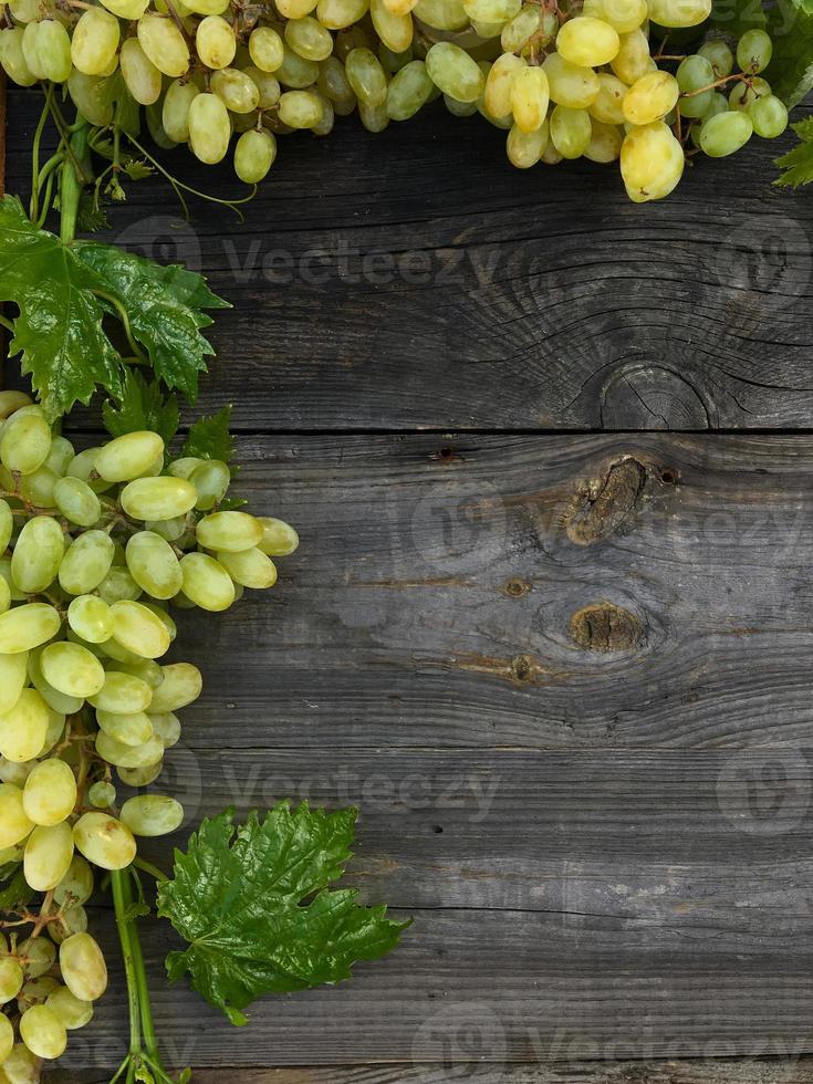 cachos de moldura de uvas em fundo cinza de madeira foto