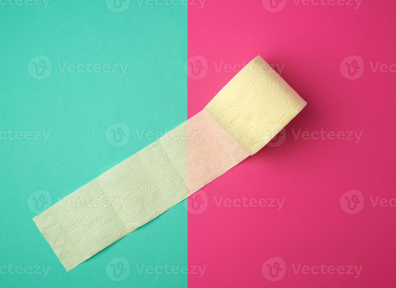 papel higiênico amarelo macio em rolo sobre fundo verde-rosa foto