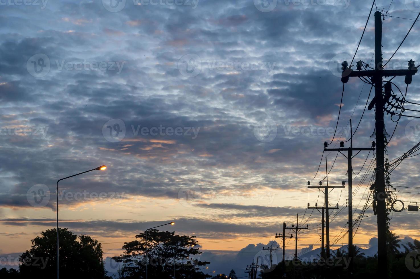 foto de silhueta de enquete elétrica com linha ou fio e muitos pássaros pequenos no topo, tirada no início da manhã ou à noite no interior da tailândia com céu nublado, cenário de paisagem do interior