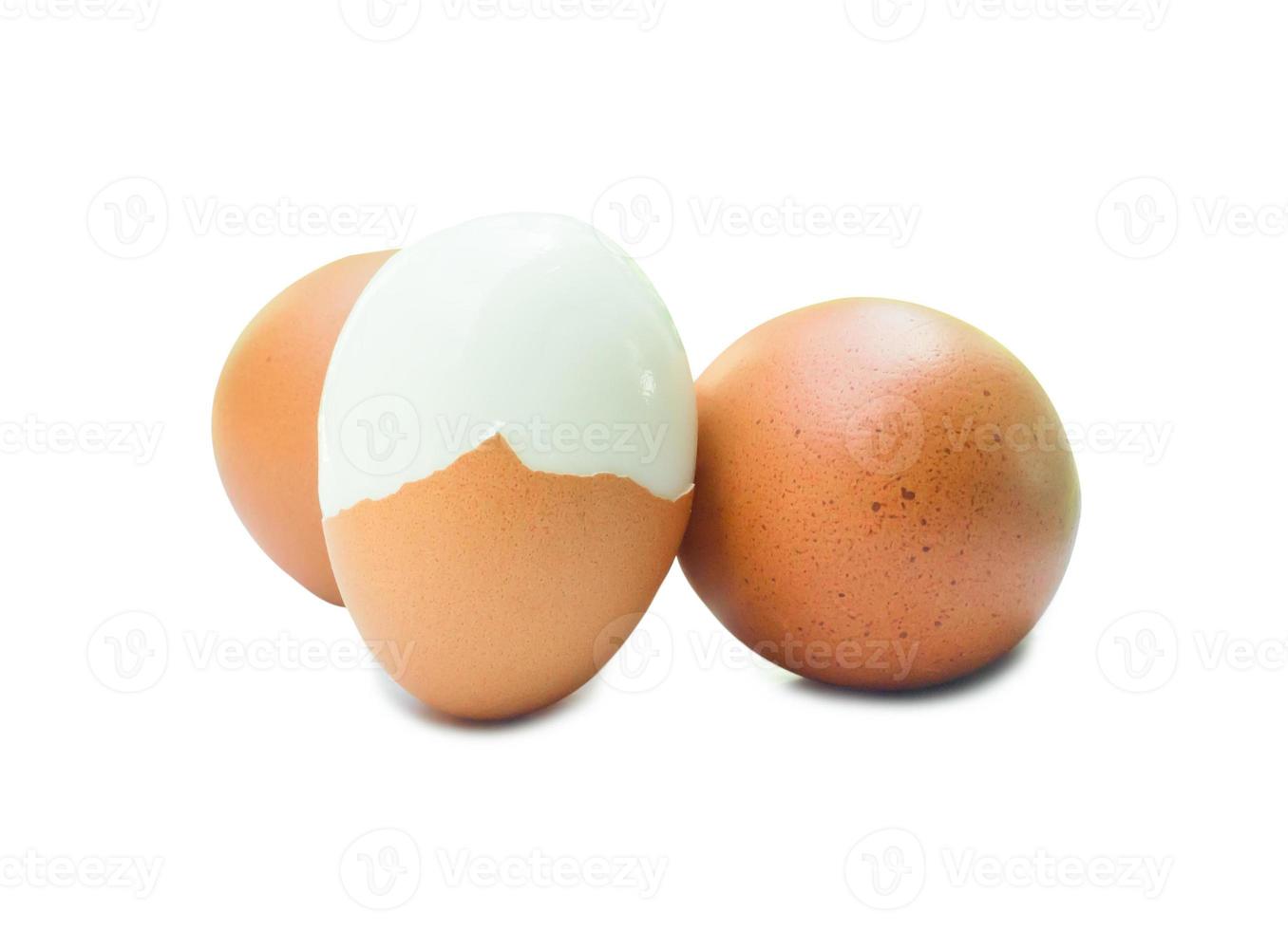 três ovos de galinha marrons frescos com uma metade descascada isolada no fundo branco com traçado de recorte, conceito de alimentação saudável de alimentos orgânicos foto