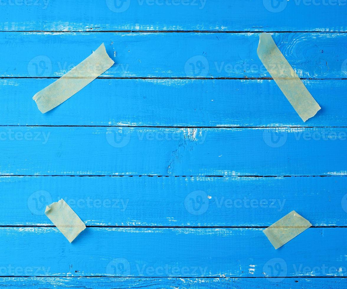 quatro pedaços de papel amarelo de fita adesiva presos nos cantos em um fundo azul de madeira foto