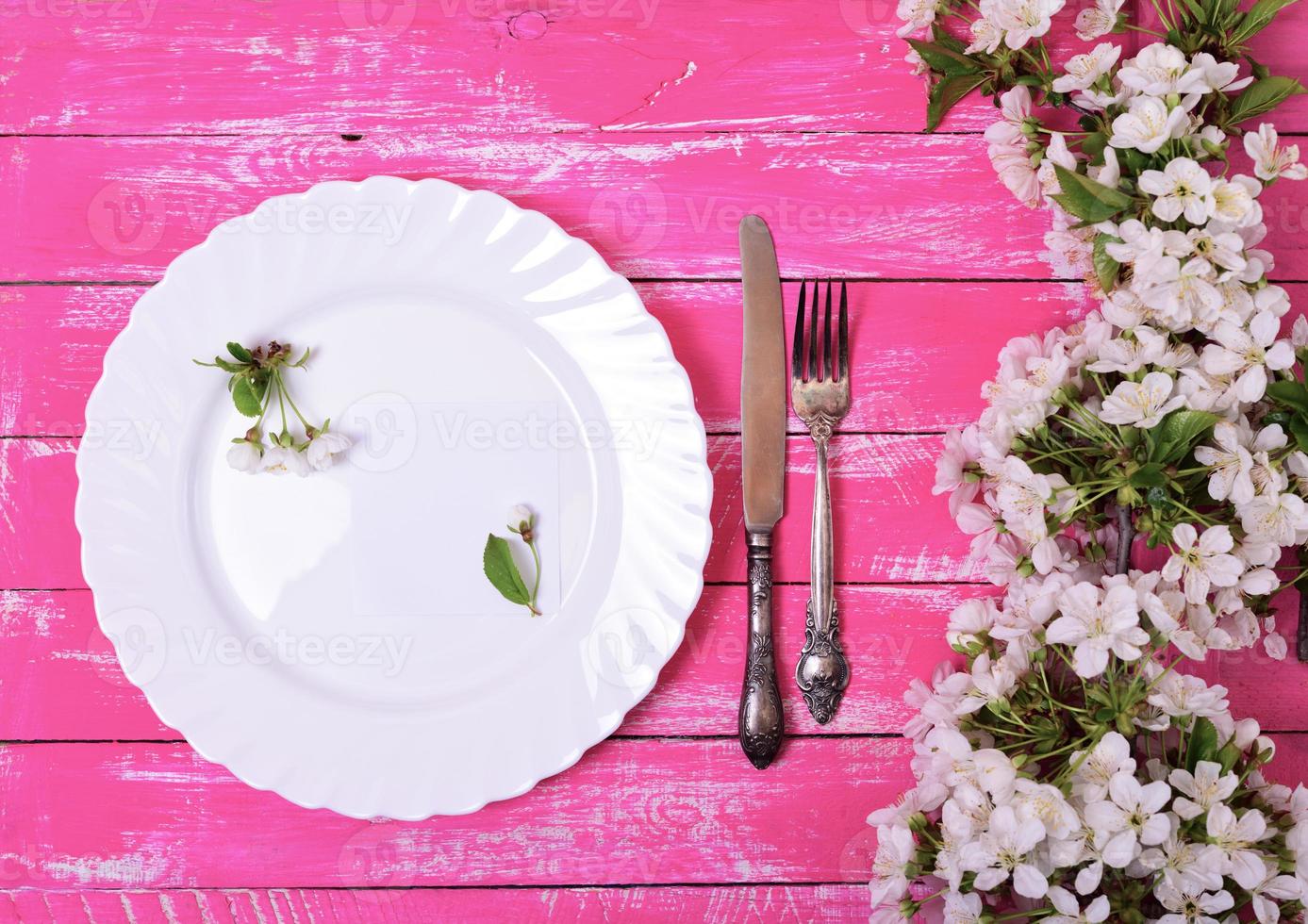 prato branco com uma nota de papel vazia em uma superfície de madeira rosa foto