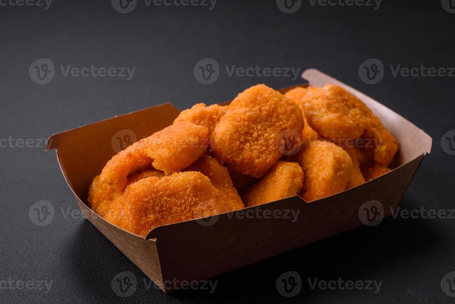 deliciosos nuggets de frango crocantes frescos em um fundo escuro de concreto foto