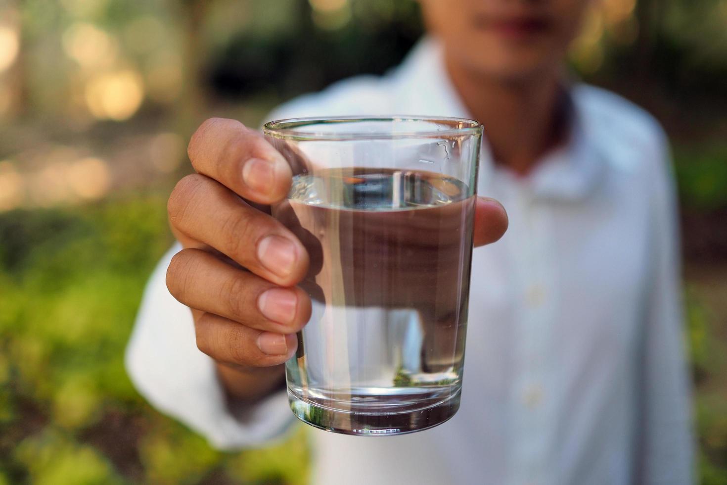 um homem segura água para beber. após o estresse do trabalho para ajudar a relaxar cansado. água benéfica foto