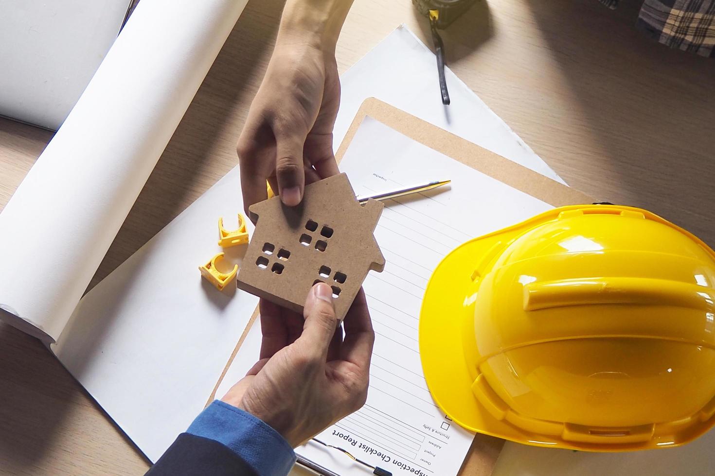 construtor de casas entrega modelos de casas aos proprietários. há documentos sobre a construção da casa e o leme de engenharia colocado sobre a mesa. foto