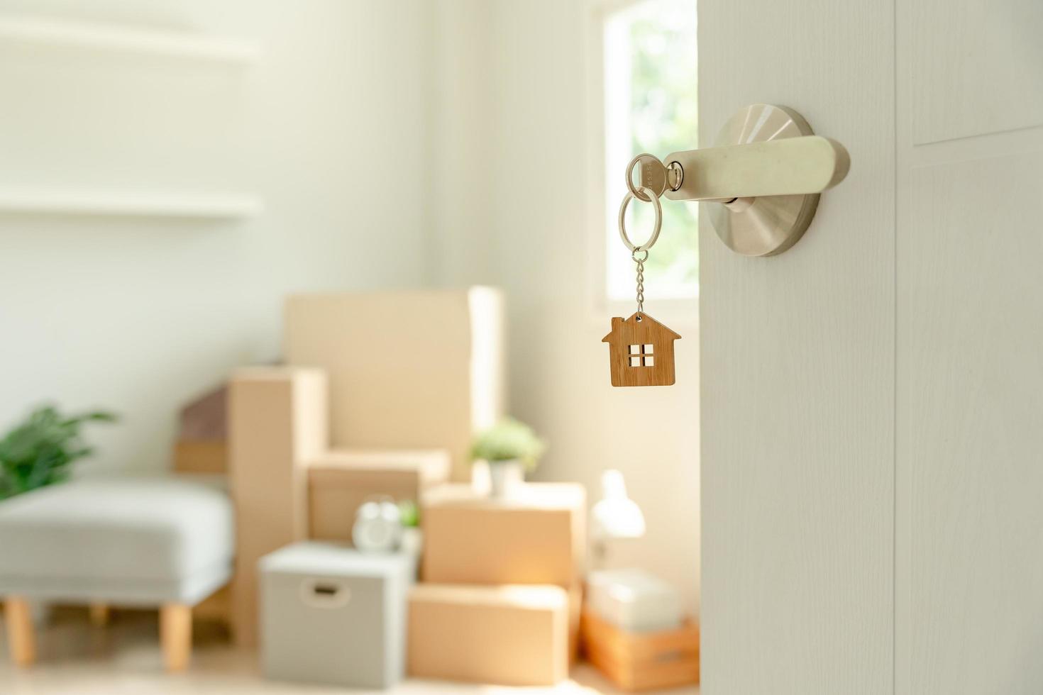 mudança de casa, realocação. a chave foi inserida na porta da nova casa, dentro do quarto havia uma caixa de papelão contendo pertences pessoais e móveis. mudar no apartamento ou condomínio foto