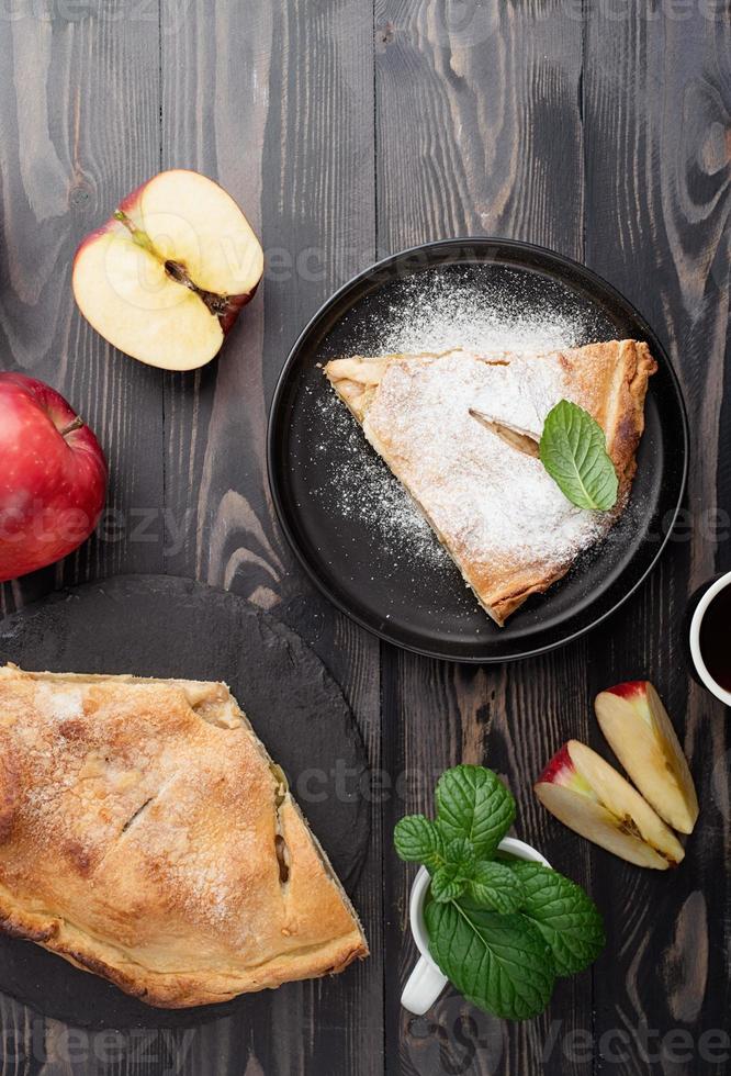 pedaço caseiro de torta de maçã com maçãs vermelhas frescas na mesa preta foto