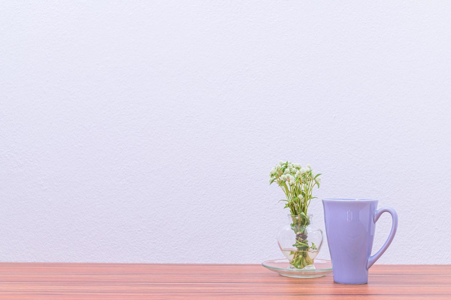 caneca de café e vaso de flores na mesa foto